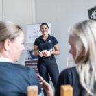 Eine Frau erklärt mit einem Modell in der Hand.